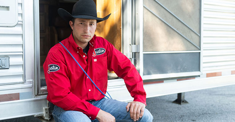 Haven Meged sitting at his trailer posing for the camera wearing a red shirt.